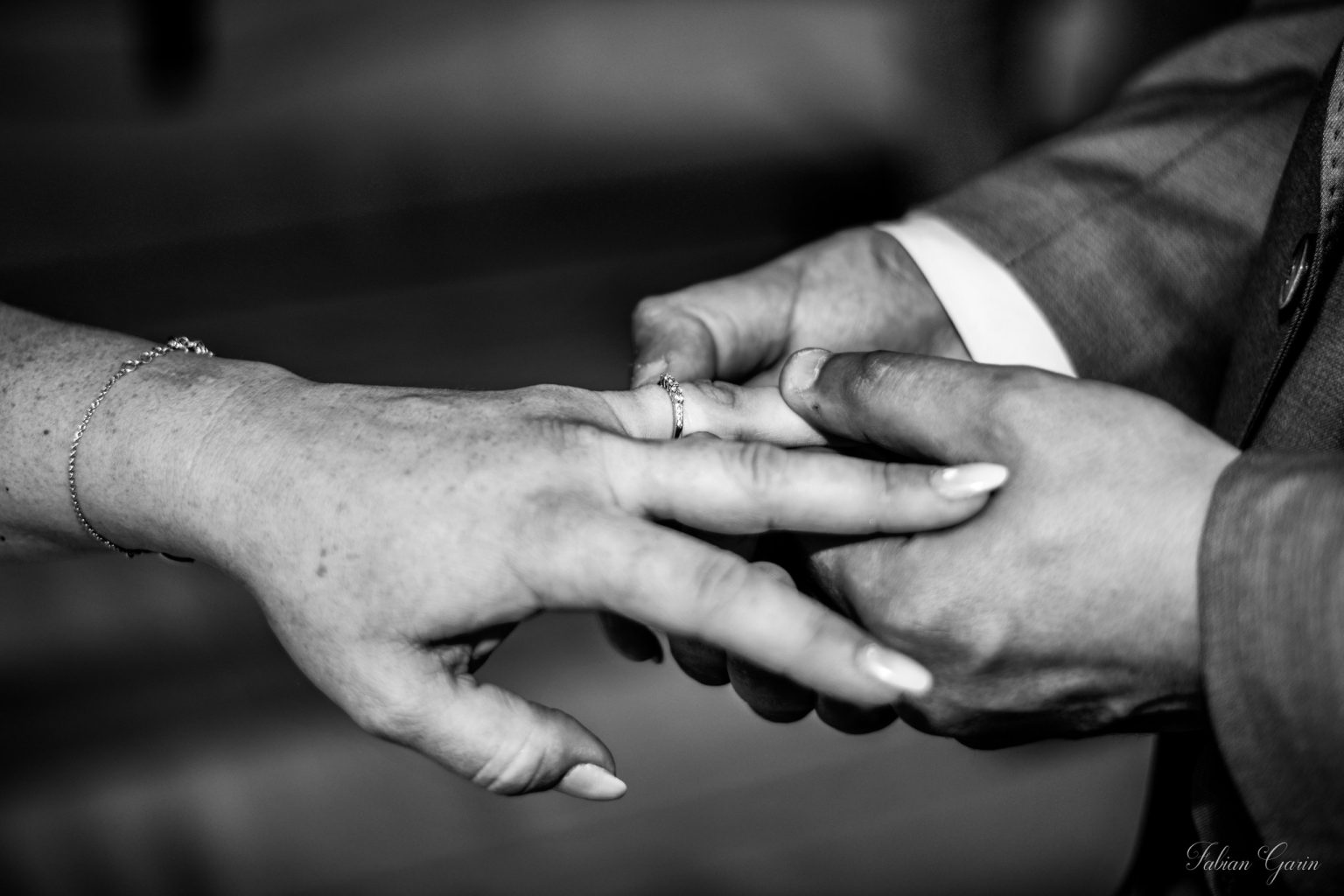 Gros plan en noir et blanc sur l’échange des alliances entre Julianna et Meadi, lors de leur cérémonie de mariage.