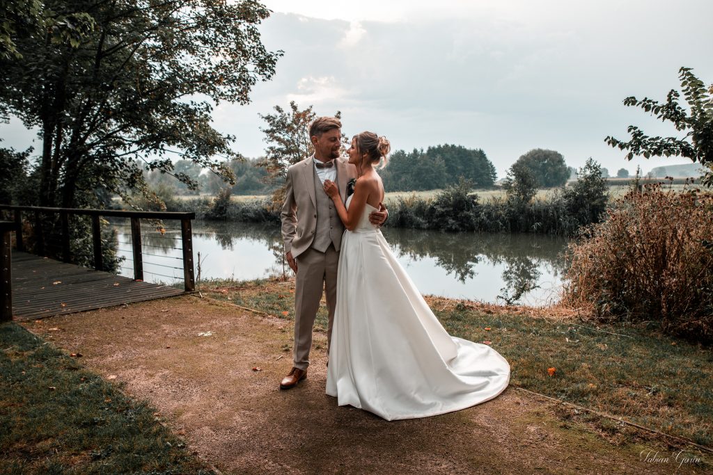 Chloé et François, jeunes mariés, se regardent avec tendresse au bord d’un plan d’eau, entourés de nature, lors de leur séance photo de mariage.